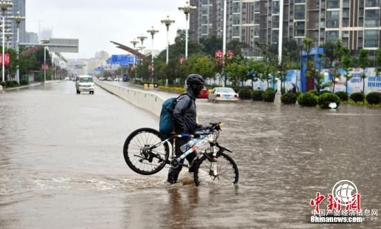 7月22日，民眾抬著自行車(chē)從積水路上走過(guò)。當(dāng)日，昆明持續(xù)降雨，城區(qū)多處路段積水。昆明市氣象臺(tái)發(fā)布暴雨藍(lán)色預(yù)警，未來(lái)12小時(shí)昆明市區(qū)及周邊多地區(qū)將持續(xù)降雨。 <a target=