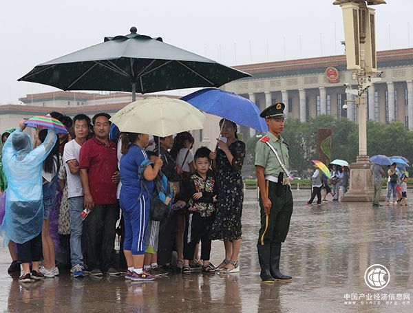 天安門廣場(chǎng)一執(zhí)勤武警將崗傘讓給群眾避雨，自己冒雨站崗